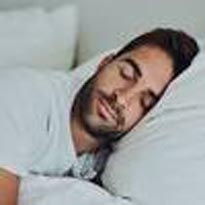 bearded younger man sleeping on white pillow